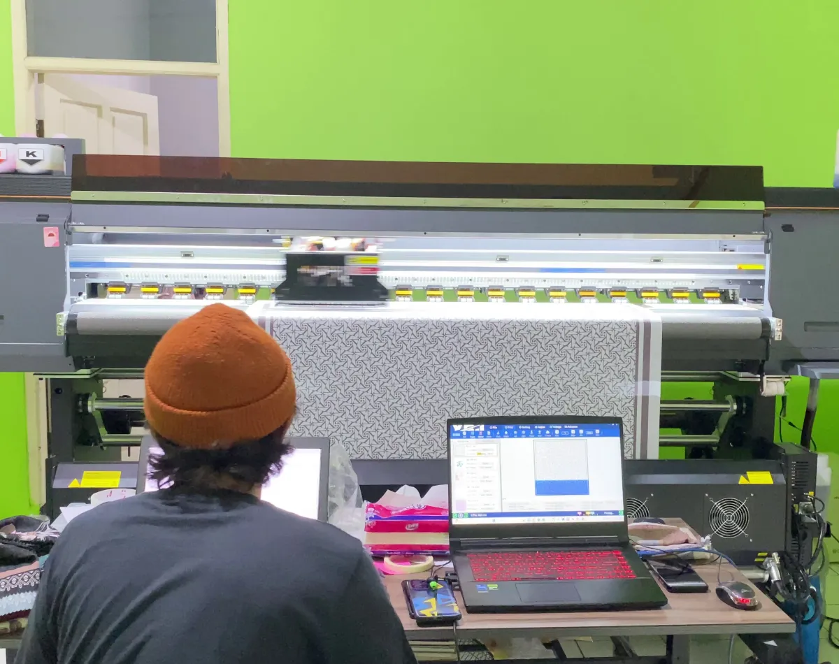 Bu Rusmini operating her digital sublimation printing machine to fulfill hijab printing orders quickly.