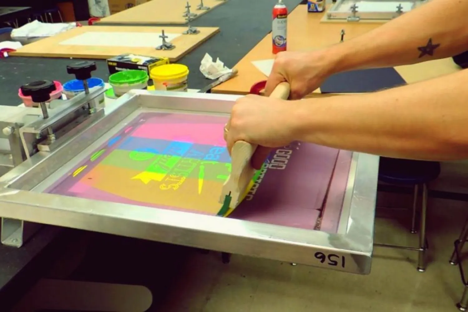 Pebisnis sablon sedang mencetak baju dengan teknik sablon plastisol.