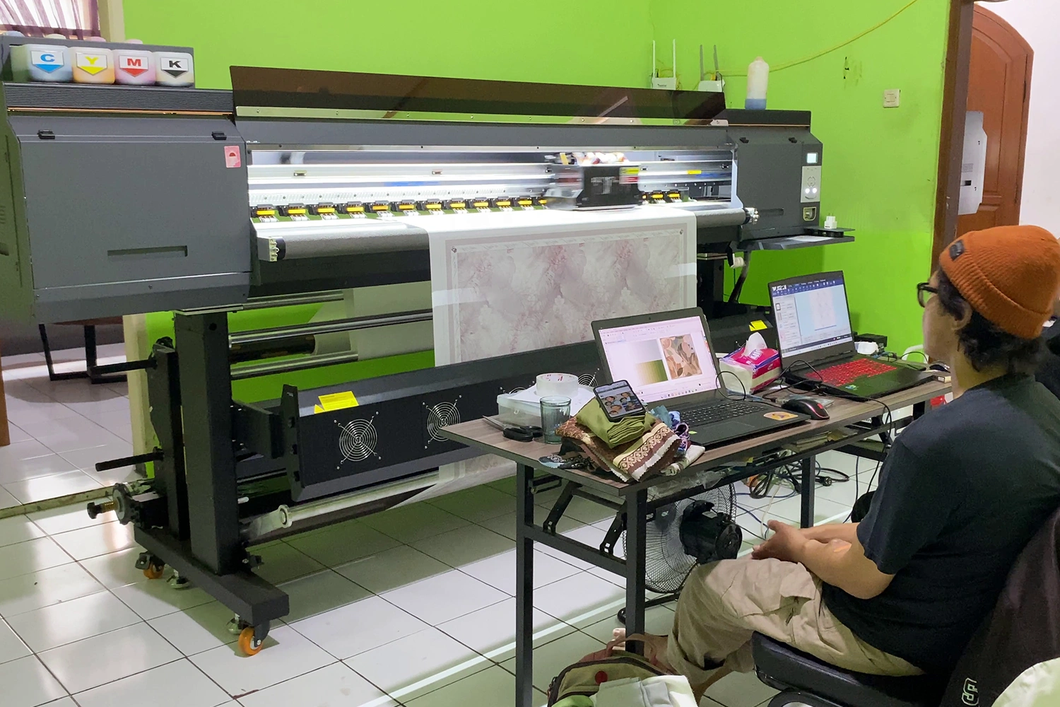 Seorang pengusaha sedang melakukan uji coba mesin printing untuk memastikan mesin tersebut sesuai dengan kebutuhannya.