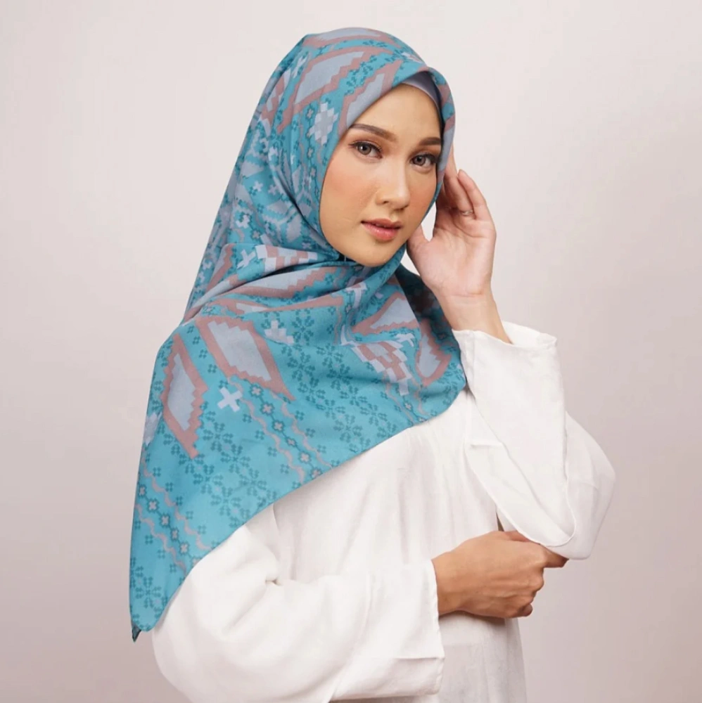 Seorang wanita menggunakan hijab dengan warna hijau tosca.