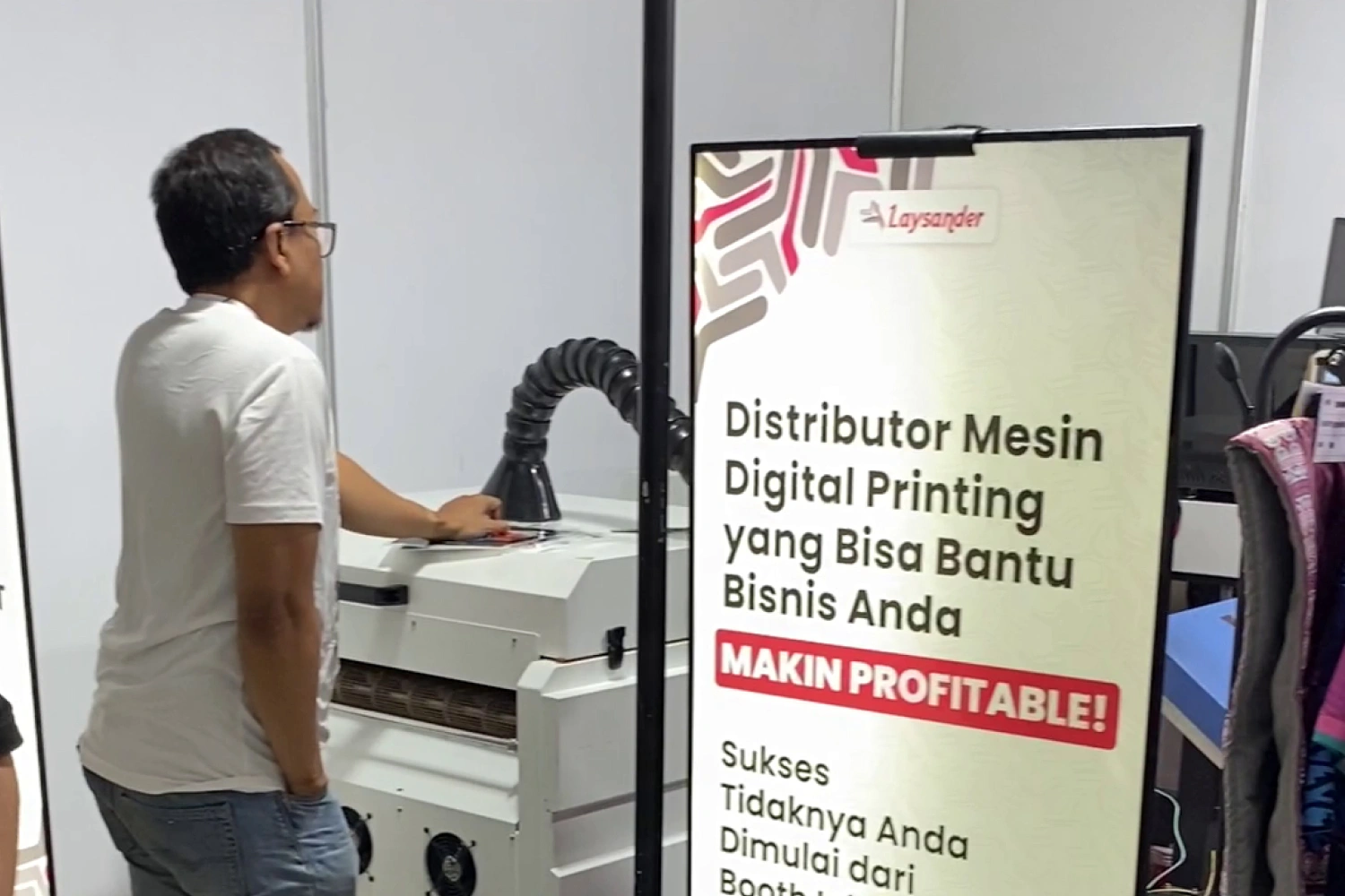 Visitors looking at printing machines at the Laysander booth during IAPE 2024