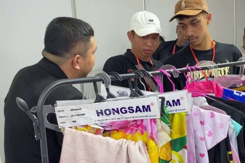 Visitors discussing apparel printing samples at IAPE 2025 exhibition booth.
