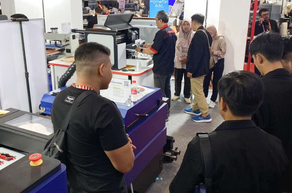 Pengunjung melihat demonstrasi mesin cetak modern di booth Laysander selama pameran All Print 2025 di JIExpo Kemayoran.