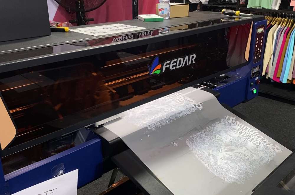 Mesin printer Fedar sedang mencetak film DTF dengan detail desain yang halus pada pameran.