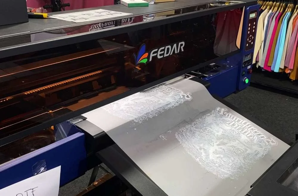 Printer DTF Fedar sedang mencetak desain pada film transfer di booth pameran Kenduri Sablon Jogja #3.
