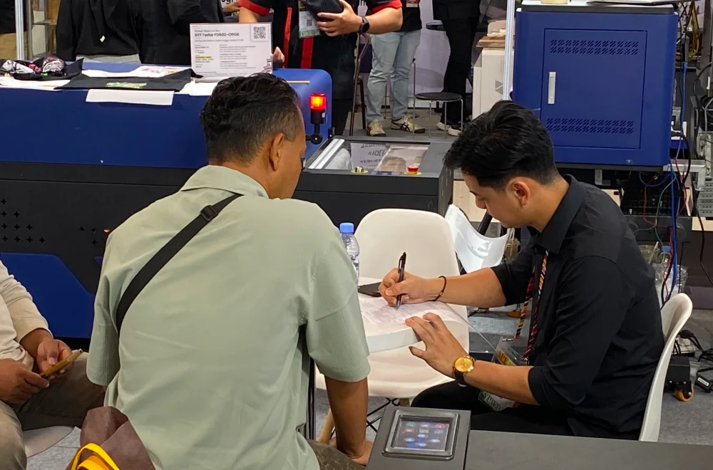 Tim exhibitor memberikan konsultasi kepada pengunjung di Surabaya Printing Expo 2026 mengenai investasi mesin cetak dan solusi bisnis percetakan.