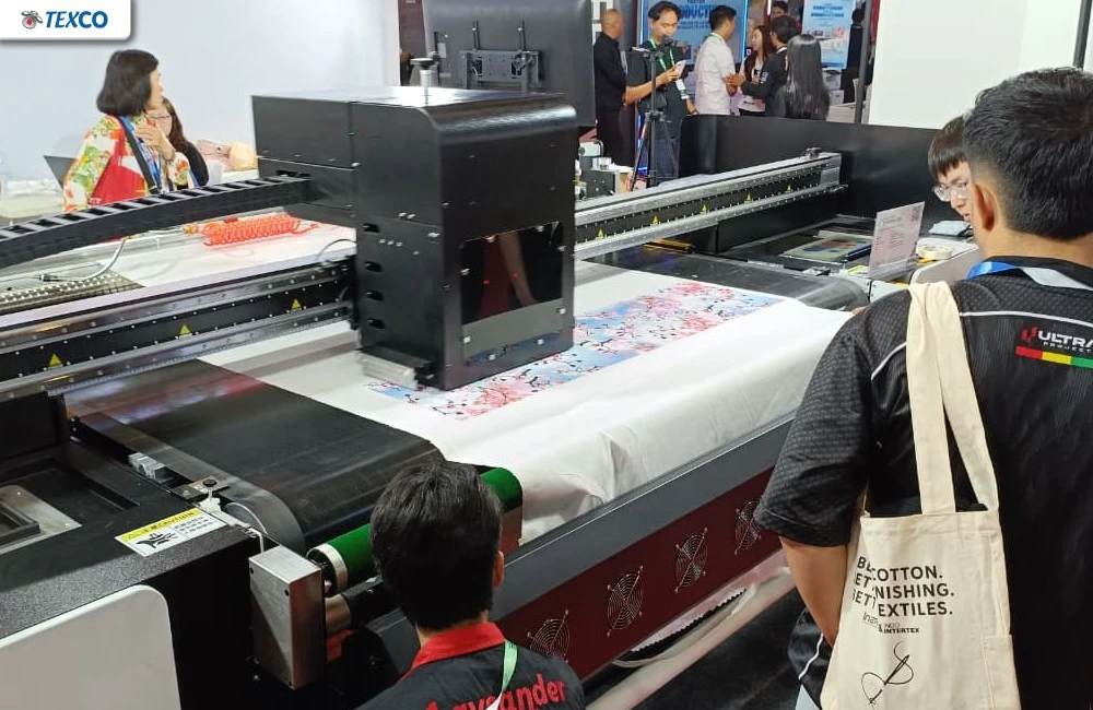 Proses test print langsung pada kain menggunakan mesin printing yang disaksikan pengunjung pameran IAPE 2026.