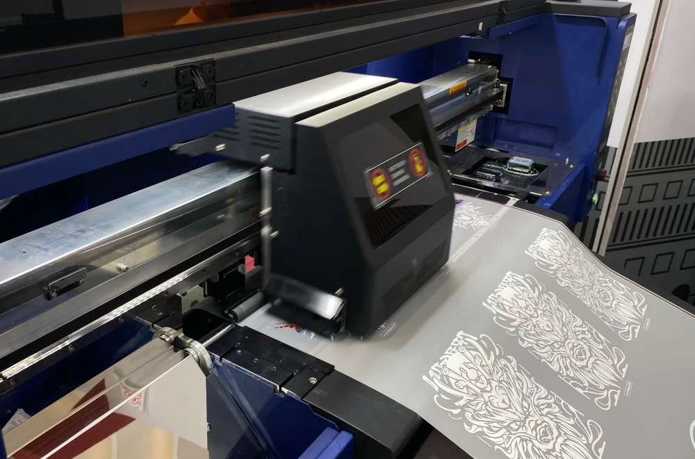 Demo mesin printing yang sedang mencetak desain di booth Laysander pada pameran IAPE Bandung 2026.